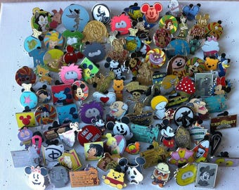 Könnte beinhalten: Eine Sammlung bunter Disney-Charakter-Anstecknadeln mit Mickey Mouse, Winnie Puuh und anderen beliebten Figuren. Die Anstecknadeln variieren in Form und Design, mit Emaille- und Metalloberflächen. Einige Anstecknadeln haben Text, und die Sammlung ist auf einer weißen Oberfläche angeordnet.
