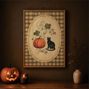 Könnte beinhalten: Ein gerahmtes Wandbild mit einem zentralen ovalen Jute-Einsatz, der eine Illustration eines orangefarbenen Kürbisses und einer schwarzen Katze zeigt, umrandet von einer cremefarbenen Häkelspitze auf einem grün-beigen karierten Hintergrund.