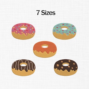 Könnte beinhalten: Ein Bild mit fünf gestickten Donuts mit verschiedenen Belägen. Die Donuts haben eine beige Basis mit verschiedenen Glasuren, darunter rosa mit Streuseln, blau mit Streuseln, orange, Schokolade mit weißen Linien und Schokolade mit braunen Punkten. Der Text "7 Sizes" steht oben.