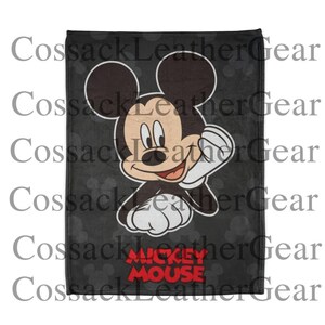 May include: A black blanket with a large illustration of Mickey Mouse waving. The blanket has a dark grey background with a subtle polka dot pattern and the words "Mickey Mouse" in red.