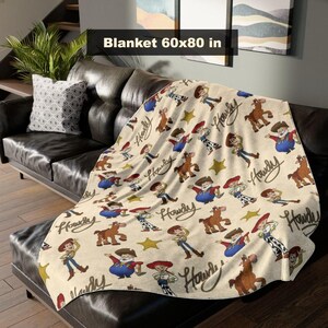 May include: A beige blanket featuring a repeating pattern of cartoon cowboys, horses, and stars. The blanket measures 152x203 cm. The word "Howdy" is written in a cursive font. The blanket is draped over a black leather sofa.