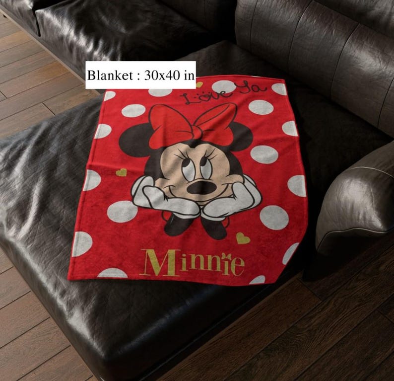May include: A red blanket with white polka dots and a Minnie Mouse graphic. The blanket, measuring 30 x 40 inches, features Minnie Mouse with a red bow and the word "Minnie" in gold lettering. The blanket also has the words "I love ya" in white.