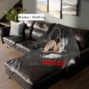 May include: A black blanket, 127x152 cm, with a large Mickey Mouse graphic. The blanket has a repeating pattern of Mickey Mouse silhouettes and the words "Mickey Mouse" in red.