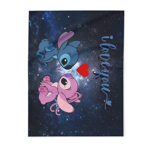 May include: A blanket featuring a blue and pink cartoon alien couple with a red heart on a dark blue background with a galaxy design. The words "i love you" are written in cursive.