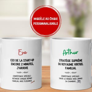 May include: Two white ceramic mugs with black handles are displayed on a wooden surface. One mug has the name "Eva" in red, with text below. The other mug has the name "Arthur" in green, with text below. A red circle with white text is above the mugs.
