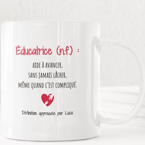 Pode incluir: Caneca de cerâmica branca com o texto "Educatrice (n.f.): AIDE À AVANCER, SANS JAMAIS LÂCHER, MÊME QUAND C'EST COMPLIQUÉ. Définition approuvée par Luca" em rosa e preto. Um gráfico de coração vermelho também está presente.