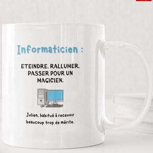 Może przedstawiać: Biały ceramiczny kubek z niebieskim napisem Informaticien, czarnym tekstem ETEINDRE. RALLUMER. PASSER POUR UN MAGICIEN., grafiką komputera oraz czarnym napisem Julien, habitué à recevoir beaucoup trop de mérite.