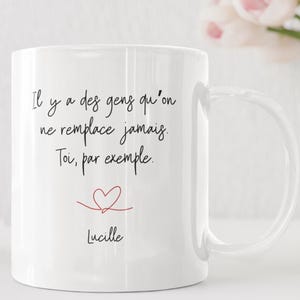 Può includere: Tazza in ceramica bianca con manico curvo. La tazza presenta una scritta nera che recita "Il y a des gens qu'on ne remplace jamais. Toi, par exemple. Lucille" con un'illustrazione di cuore rosso.