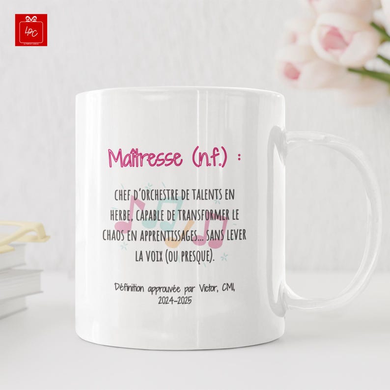 Pode incluir: Caneca de cer&acirc;mica branca com uma al&ccedil;a curva. A caneca apresenta o texto "Ma&icirc;tresse (n.f.): CHEF D'ORCHESTRE DE TALENTS EN HERBE, CAPABLE DE TRANSFORMER LE CHAOS EN APPRENTISSAGES... SANS LEVER LA VOIX (OU PRESQUE)."