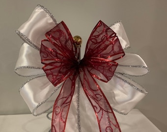 Christmas wreath decorative bow white satin w/ tinsel edging and a sheer burgundy ribbon with burgundy glitter swirls .