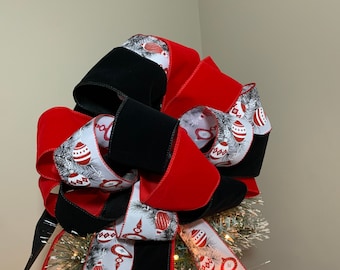 Large Christmas tree topper bow made with a red and a black velour ribbon and a coordinating white ribbon with ornaments