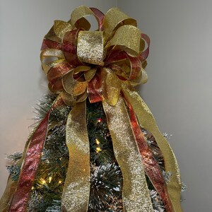 May include: A gold and burgundy Christmas tree topper bow with a large, glittery bow and streamers.