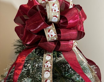 Large Christmas tree topper bow made with a natural burlap ribbon printed w/ Santa and snow flakes and coordinating dark red  ribbon