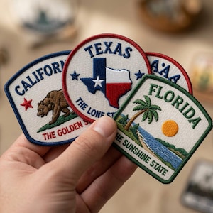 Peut inclure: Trois écussons brodés sur le thème des États américains. Un écusson circulaire montre le drapeau du Texas. Un écusson de Californie affiche un ours brun et une étoile rouge. Un écusson en forme de bouclier de Floride représente un palmier.
