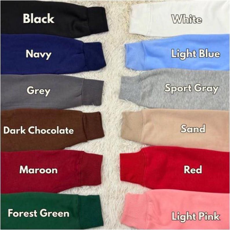 Pu&ograve; includere: Una selezione di maniche di felpa in vari colori, tra cui nero, blu navy, grigio, cioccolato fondente, bordeaux, verde foresta, bianco, azzurro, grigio sportivo, sabbia, rosso e rosa chiaro. Ogni manica mostra il nome del colore in testo bianco.