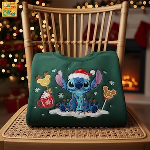 May include: A dark green sweatshirt featuring an embroidered image of Stitch wearing a Santa hat and Christmas lights. The design includes snowflakes, a reindeer cookie, and a cup of hot cocoa. The sweatshirt is displayed on a wooden chair.
