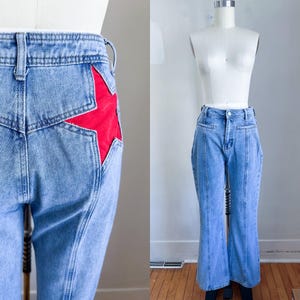 May include: Light wash denim jeans with a red star accent on the back pocket. The jeans have a high waist and a flared leg. The jeans are displayed on a mannequin.