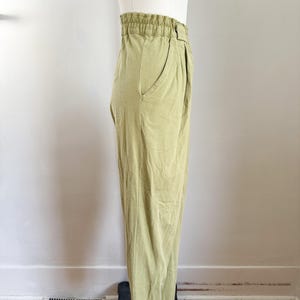 May include: Light green pants with an elastic waistband and a single pocket. The pants are made of a soft, flowing fabric and have a relaxed fit. The pants are displayed on a mannequin.