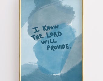 May include: A framed art print with a gold frame. The artwork features a blue watercolor background with the text "I KNOW THE LORD WILL PROVIDE" in dark blue lettering. The art print is displayed against a white background.