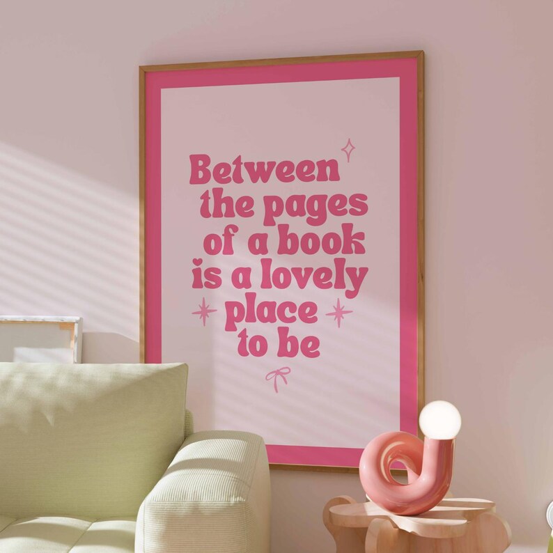 May include: A framed pink and white poster with the text "Between the pages of a book is a lovely place to be." The poster is in a room with a light green sofa and a pink lamp.