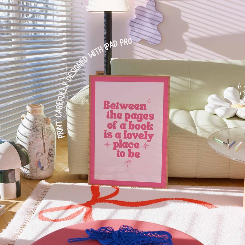 May include: A framed pink print with the text "Between the pages of a book is a lovely place to be." The print is in a room with a rug, a sofa, and a lamp.