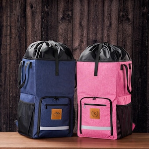 May include: Two upright tote bags, one navy blue and one pink. Both have black detailing, a drawstring top, and a front pocket with a personalised patch. Each bag features a reflective stripe and side mesh pockets.