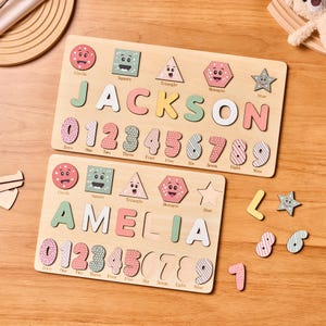 Pode incluir: Dois quebra-cabeças de madeira com os nomes "JACKSON" e "AMELIA", com letras, números e formas coloridas. Peças de quebra-cabeça adicionais espalhadas em uma superfície de madeira.