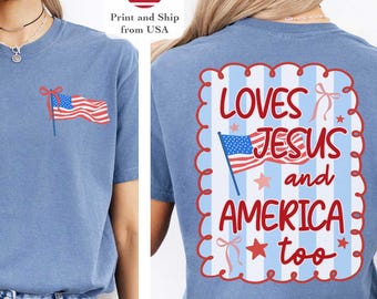 May include: A light blue t-shirt with a small American flag graphic on the front and the text "LOVES JESUS and AMERICA too" on the back. The shirt is paired with blue jeans.