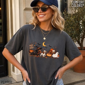 May include: A charcoal gray short-sleeve t-shirt featuring a Halloween-themed graphic of four dachshunds dressed in costumes, including a witch, a mummy, a hot dog, and a ghost, surrounded by pumpkins, bats, and a crescent moon under a sign.