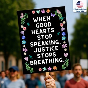 Puede incluir: Un cartel negro de protesta con el texto "WHEN GOOD HEARTS STOP SPEAKING, JUSTICE STOPS BREATHING." El cartel est&aacute; decorado con flores y hojas de colores. El cartel se sostiene en una multitud.