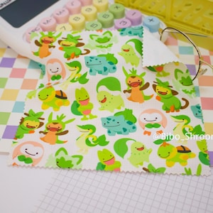 May include: White cleaning cloth featuring a repeating pattern of cartoon characters in shades of green, orange, and blue. The cloth has a scalloped edge and the text "@Bibo_Shroom" is visible.