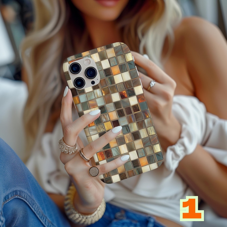 May include: A mosaic-patterned phone case in shades of gold, brown, and cream. The case has a square tile design and a camera cutout. The phone case is held in a person's hands, with multiple rings and a bracelet visible.