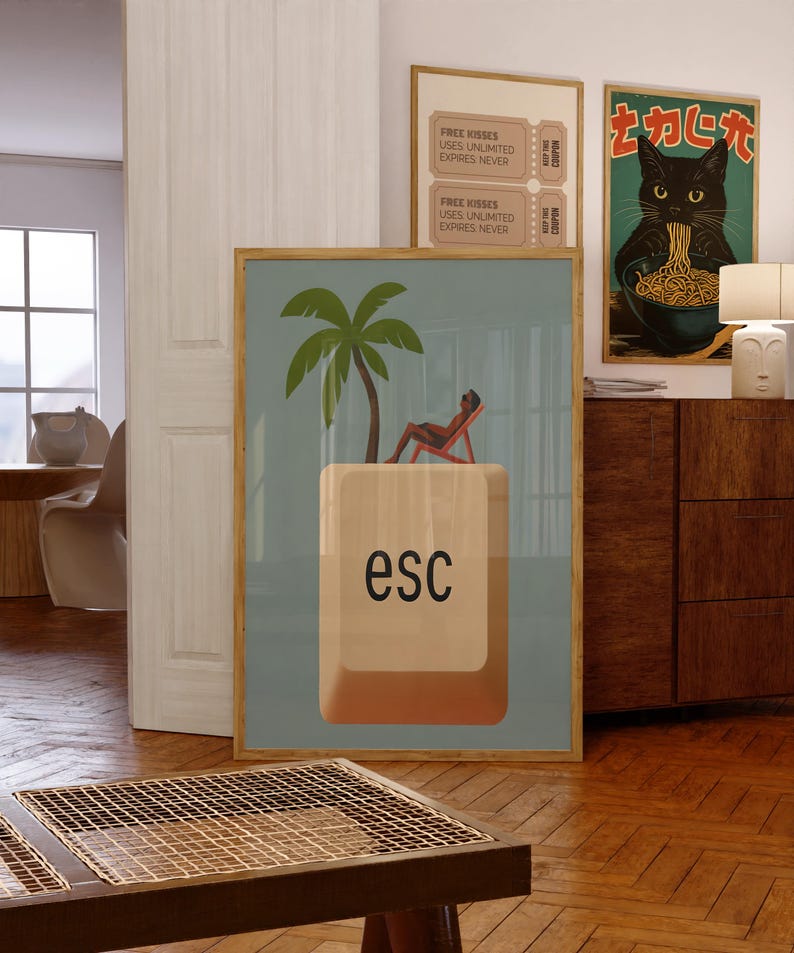 Framed whimsical poster featuring a person lounging under a palm tree on a giant “esc” keyboard key, styled in a cozy interior with playful and modern artwork.
