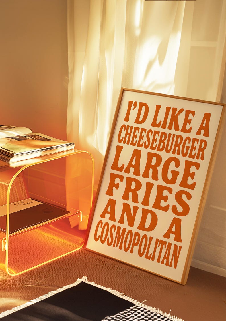 Cheeseburger and cosmopolitan poster glowing in golden hour light beside a translucent orange table and soft curtains.