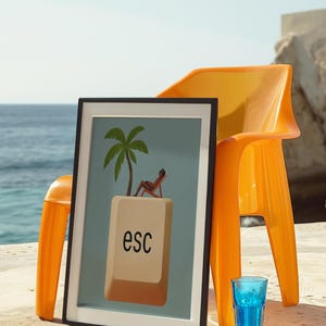Framed escape key art on a seaside patio next to bright orange chair and blue glass – bold and playful beach decor.