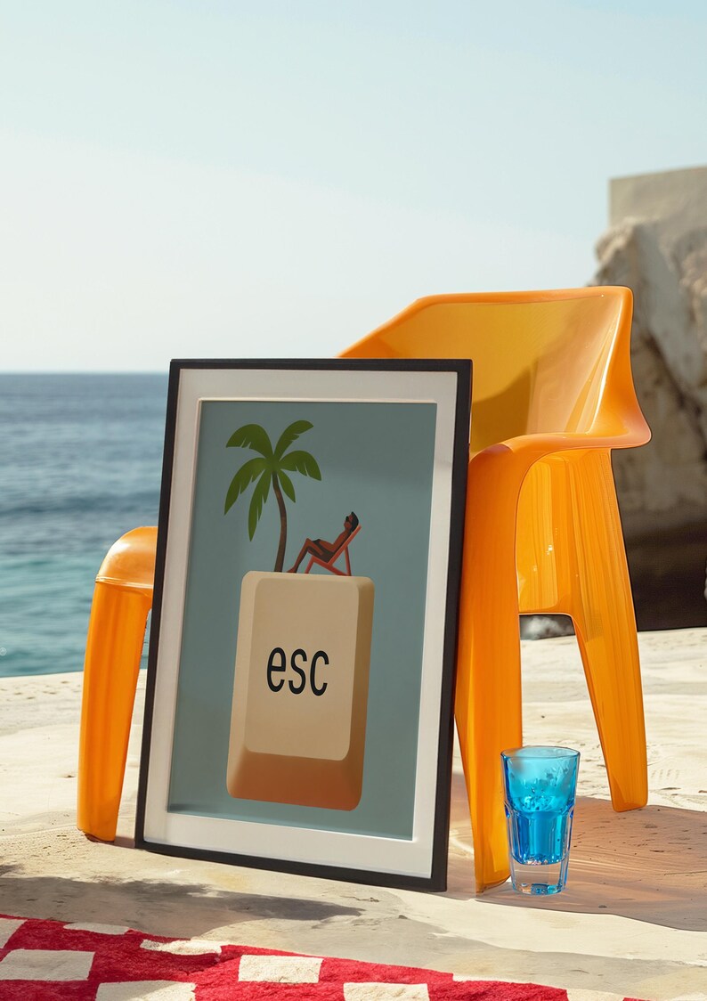 Framed escape key art on a seaside patio next to bright orange chair and blue glass – bold and playful beach decor.