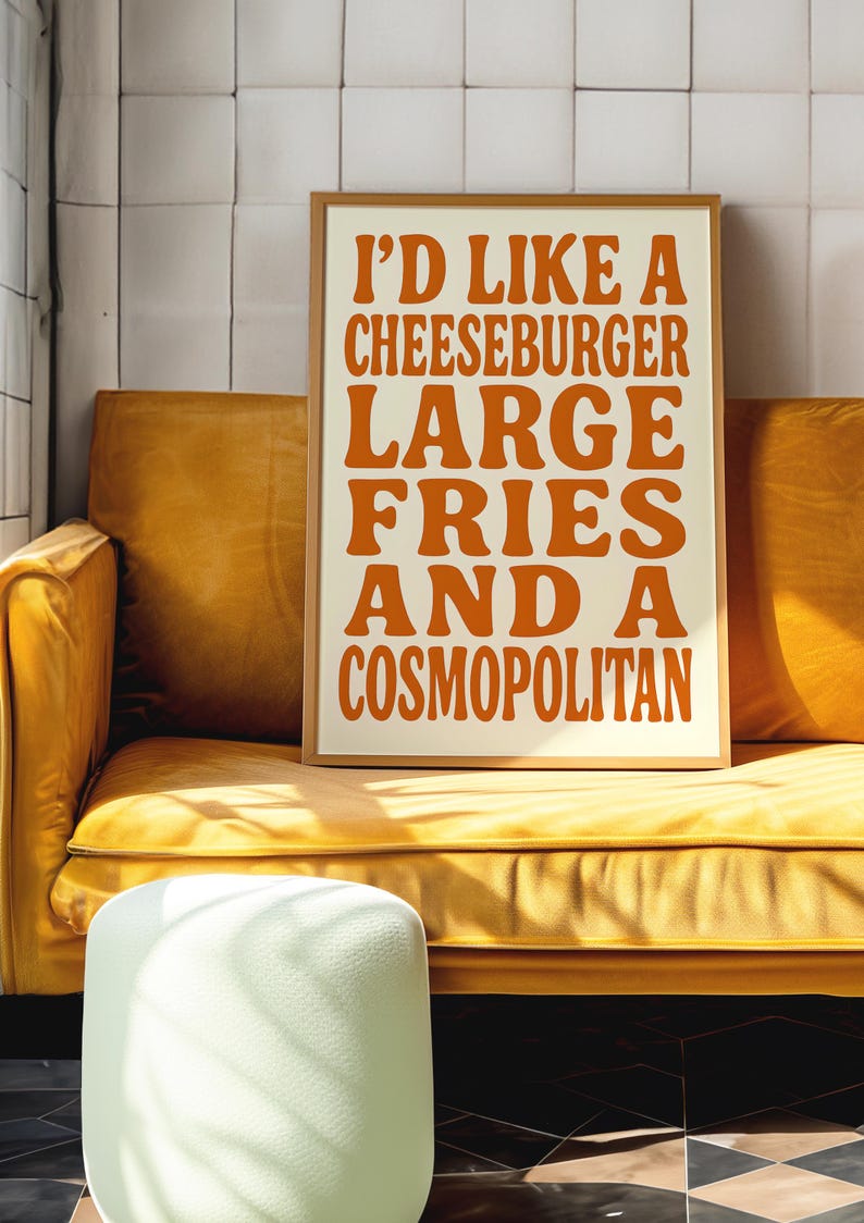 Funny orange quote poster leaning on a yellow couch, styled in a modern interior with tiled wall and sunlight.