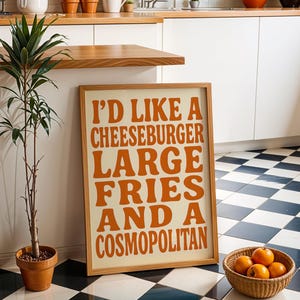Bold orange food typography poster in modern kitchen with checkerboard floor and wooden accents.