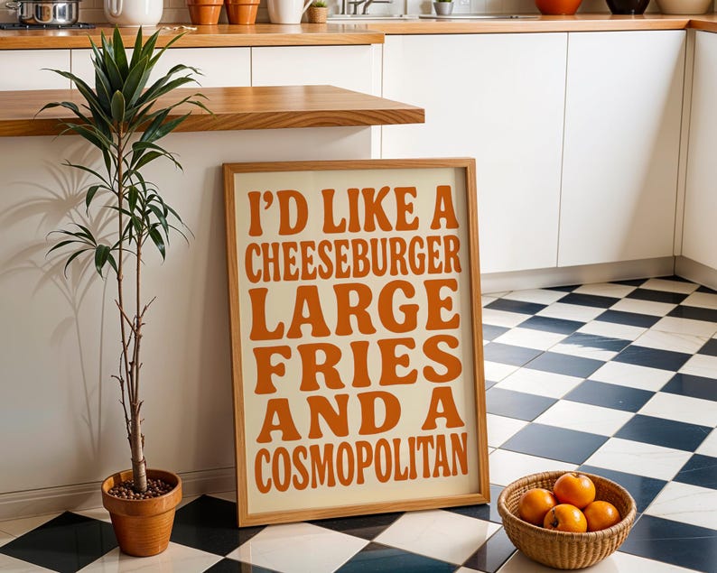 Bold orange food typography poster in modern kitchen with checkerboard floor and wooden accents.