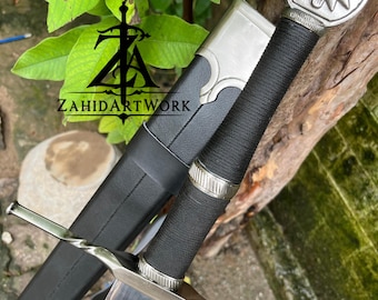 May include: A silver-colored sword with a black wrapped handle and a wolf head emblem on the pommel. The sword features a twisted crossguard and a metallic blade, accompanied by a black scabbard with silver accents and the text ZAHIDARTWORK.