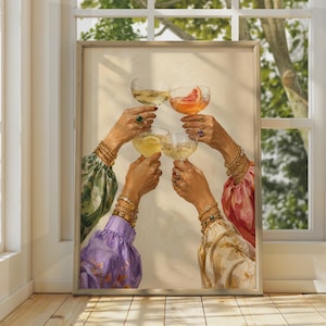 May include: A framed wall art print depicting four hands raised in a toast, each holding a stemmed glass filled with colorful beverages. The hands are adorned with multiple gold bracelets and rings, and the arms are covered in patterned fabric sleeves.