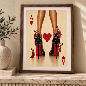 May include: A framed art print featuring a playing card design with a large red heart in the centre and the letter A in the corners. The image displays two legs wearing black high-heeled shoes with red soles, surrounded by small figures in red dresses.