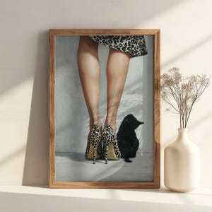 May include: A framed wall art print depicting a pair of legs wearing leopard print high-heeled pumps and a matching leopard print skirt, standing next to a small black cat. The scene is rendered in a realistic style with soft lighting and shadows.