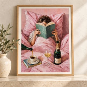 May include: An oil painting in a wooden frame depicting a person reading a green book while lying in pink bedding. A dark bottle pours liquid into a white teacup resting on a book, next to a glass of white wine and a champagne bottle.