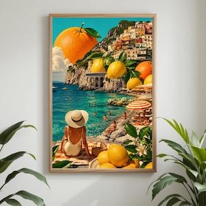 Könnte beinhalten: Gerahmter Kunstdruck, der eine Küstenlandschaft mit einer großen Orange und Zitronen zeigt. Eine Person in einem weißen Badeanzug und Sonnenhut sitzt auf einem gestreiften Handtuch und blickt auf das türkisfarbene Wasser. Der Hintergrund zeigt ein Bergdorf und Sonnenschirme.