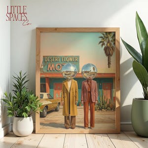 May include: A framed art print featuring two figures with disco ball heads standing in front of a Desert Flower Motel. The figure on the left wears a long yellow coat and brown trousers, while the figure on the right wears a pink blazer and trousers.