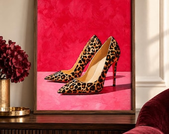 Op de afbeelding: Een ingelijste kunstdruk met een paar pumps met hoge hakken en een spitse neus met een bruin en zwart luipaardpatroon. De schoenen staan tegen een levendige, getextureerde magentakleurige achtergrond en ondergrond.