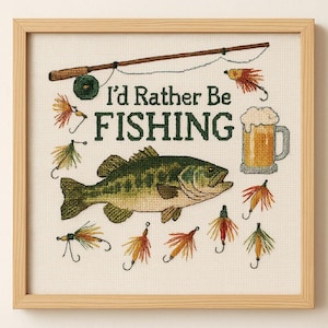 May include: Cross-stitch artwork in a wooden frame with a fishing theme. The design includes a fish, fishing rod, beer mug, and the text "I'd Rather Be Fishing." Colourful fishing lures are also included in the design.