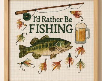 May include: Cross-stitch artwork in a wooden frame featuring a fishing theme. The design includes a fish, fishing rod, beer mug, and the text "I'd Rather Be Fishing." Colorful fishing lures are also included in the design.