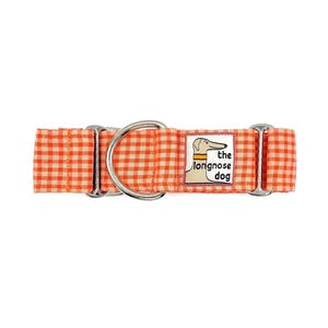 Puede incluir: Un collar para perro con estampado de cuadros vichy naranja y blanco, que incluye una anilla en D de metal plateado y un parche rectangular de tela con la ilustración de un perro y el texto "the longnose dog" en letras negras.